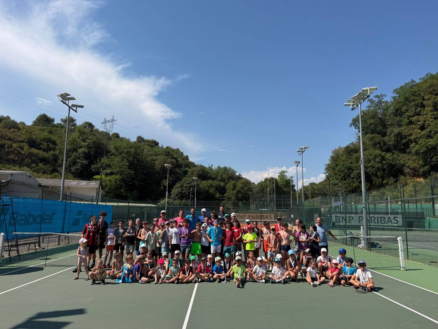 Groupe d'élèves de l'école de tennis réunis sur le court