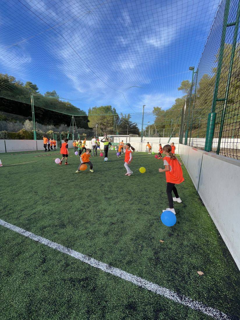 Enfants jouant avec des ballons sur le terrain de five