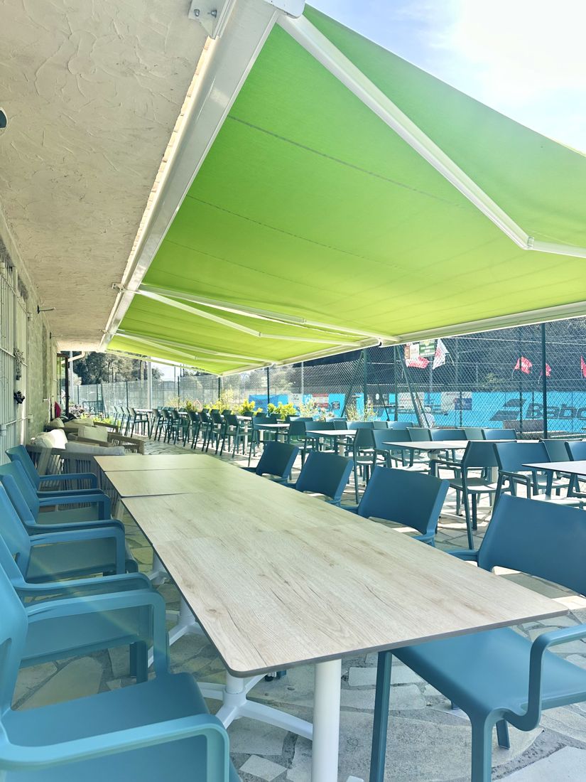 Terrasse ombragée du clubhouse avec vue sur les courts